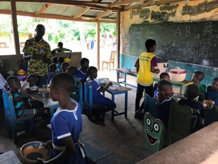 Schoolchildren receiving meals in a classroom